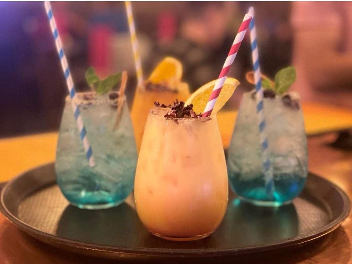 Three pastel cocktails with striped straws on a copper tray
