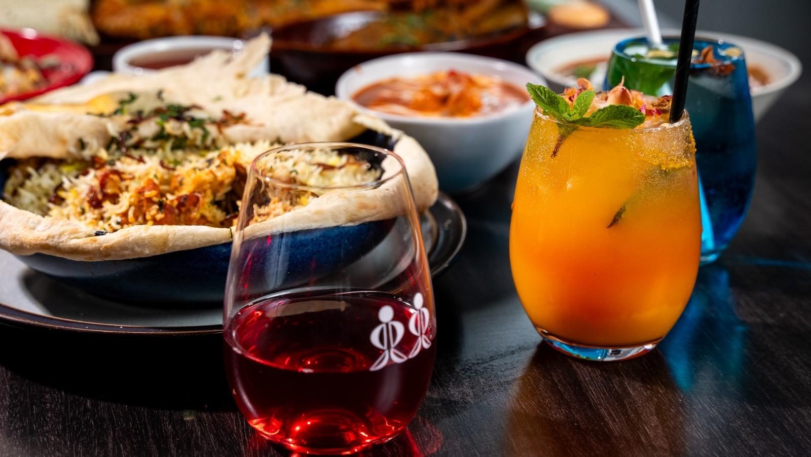 Curries, naan and cocktails on a dark table