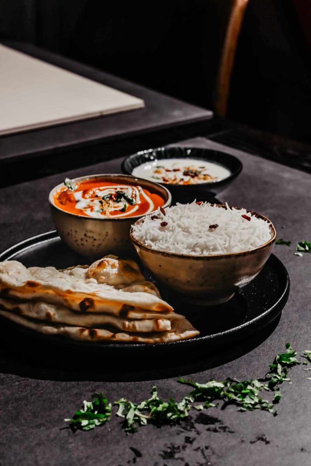 Curries, rice and naan on a dark tray