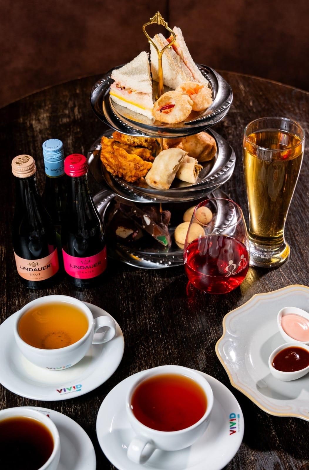 Full high tea spread with tiered stand, teas and drinks
